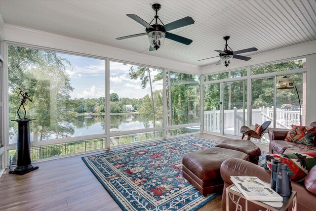 sunroom / solarium featuring ceiling fan and a water view