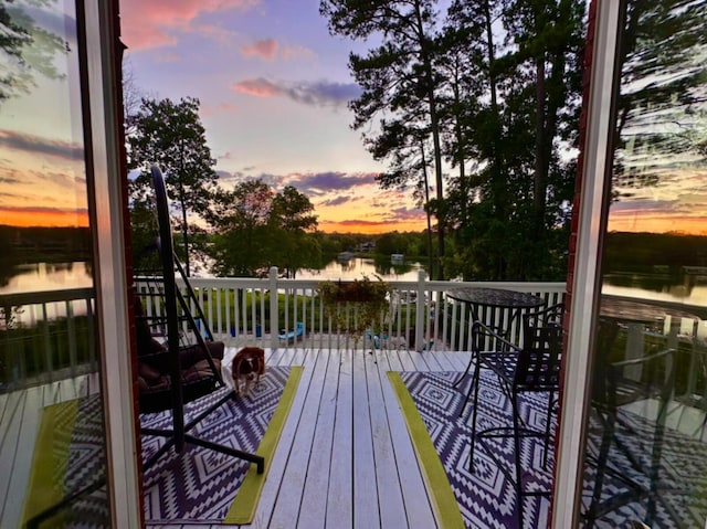 deck at dusk featuring a water view