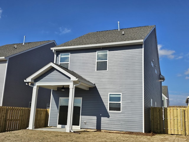 rear view of house featuring a patio, a shingled roof, and fence