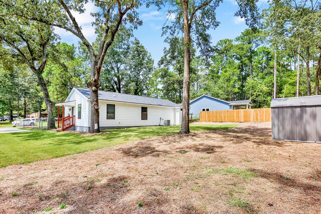 rear view of property featuring a lawn, central AC, and an outbuilding