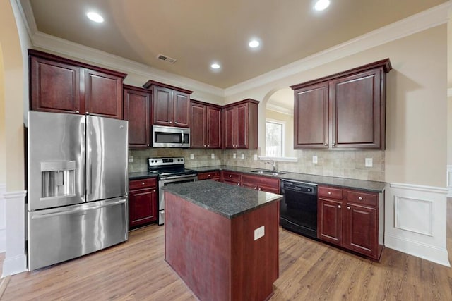 1217 Berkley Hills Pass, Evans, GA 30809 - kitchen featuring stainless steel appliances, a sink, a kitchen island, arched walkways, and light wood finished floors