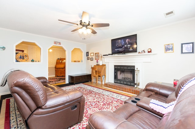 living room with ceiling fan, ornamental molding, a fireplace, and wood-type flooring