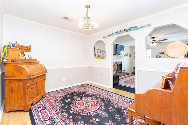 living area featuring ornamental molding, ceiling fan with notable chandelier, and light wood-type flooring