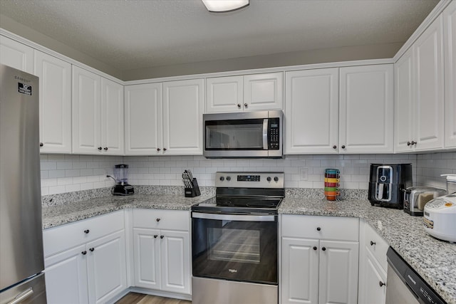 kitchen featuring tasteful backsplash, stainless steel appliances, and white cabinetry