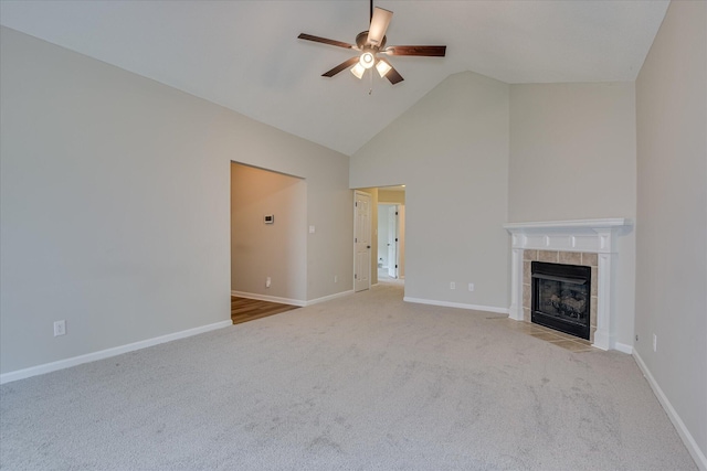 unfurnished living room featuring carpet flooring, baseboards, high vaulted ceiling, a tile fireplace, and a ceiling fan