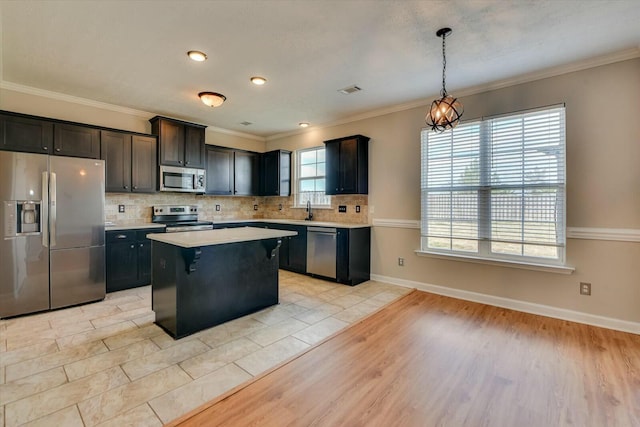 kitchen featuring a center island, decorative light fixtures, tasteful backsplash, light countertops, and appliances with stainless steel finishes