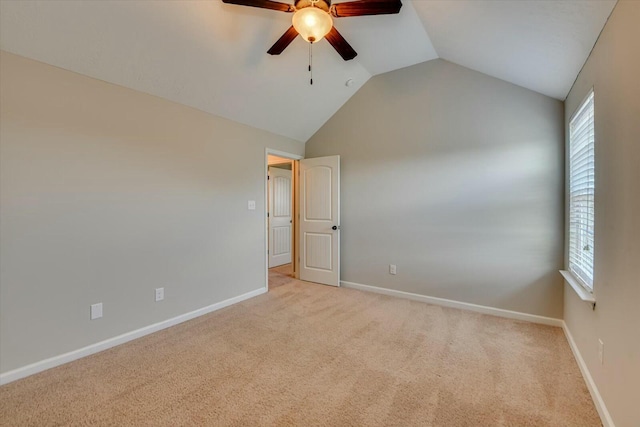 empty room featuring lofted ceiling, ceiling fan, baseboards, and light colored carpet