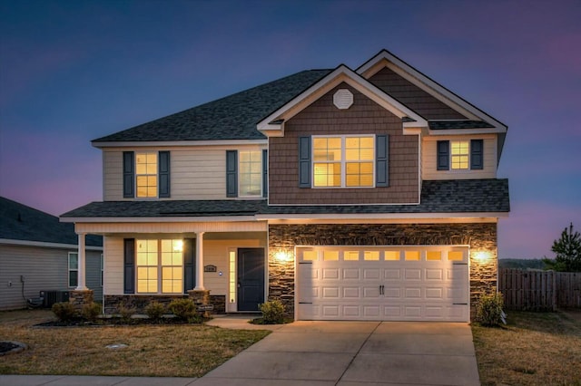 craftsman-style home with driveway, stone siding, fence, roof with shingles, and an attached garage