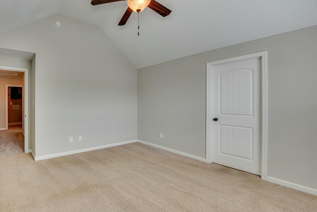 spare room featuring ceiling fan, baseboards, vaulted ceiling, and light colored carpet