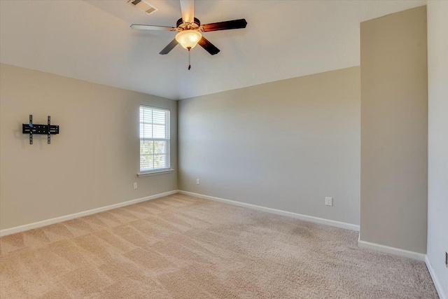 empty room with baseboards, vaulted ceiling, visible vents, and light colored carpet