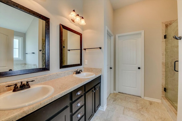 bathroom with double vanity, a stall shower, baseboards, and a sink