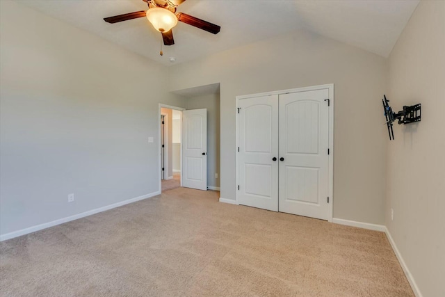 unfurnished bedroom with vaulted ceiling, a closet, light colored carpet, and baseboards