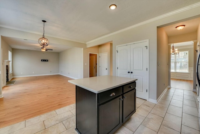 kitchen featuring a fireplace with raised hearth, light tile patterned floors, a kitchen island, light countertops, and dark cabinetry