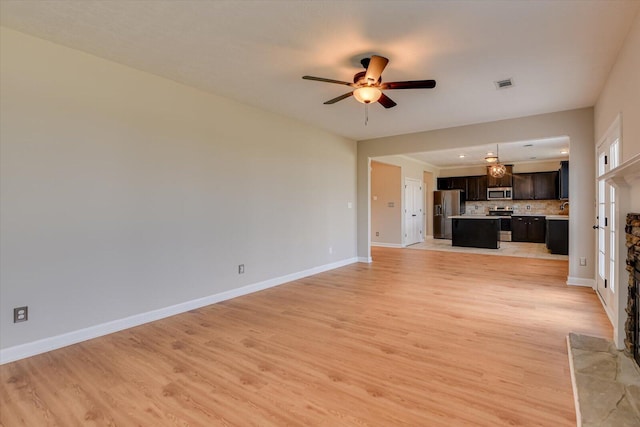 unfurnished living room with a ceiling fan, baseboards, visible vents, and light wood finished floors