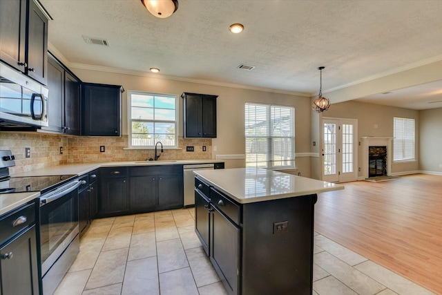 kitchen with stainless steel appliances, a sink, visible vents, a kitchen island, and light countertops