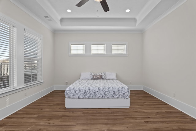 unfurnished bedroom with a tray ceiling, visible vents, and dark wood finished floors