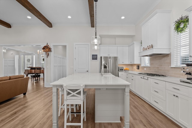 kitchen featuring tasteful backsplash, beamed ceiling, stainless steel appliances, and light wood-style floors