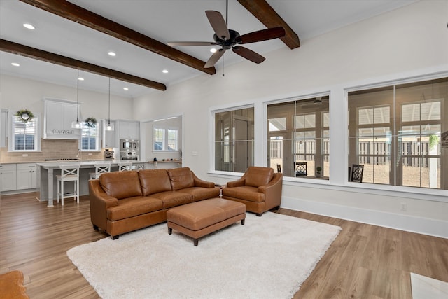 living room featuring beam ceiling, baseboards, light wood-type flooring, and ceiling fan