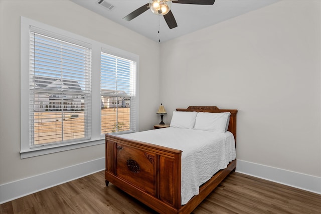 bedroom featuring a ceiling fan, wood finished floors, visible vents, and baseboards