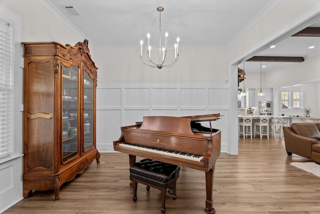 living area featuring crown molding, a decorative wall, light wood-style flooring, and visible vents