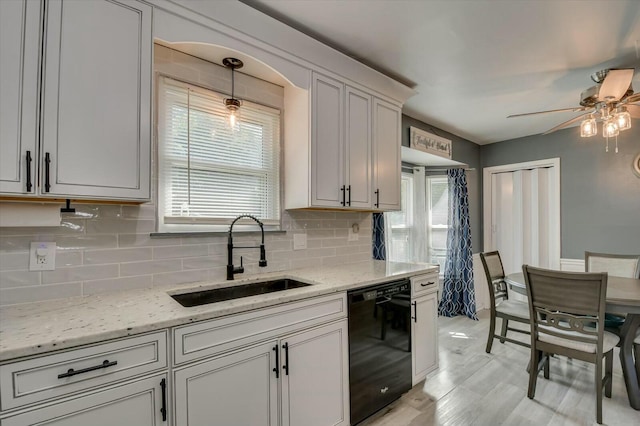 kitchen featuring decorative light fixtures, dishwasher, sink, white cabinets, and light stone counters