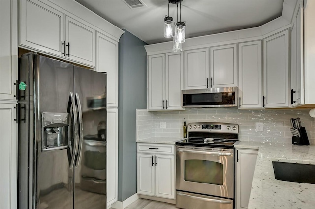 kitchen with pendant lighting, light stone countertops, white cabinetry, and stainless steel appliances