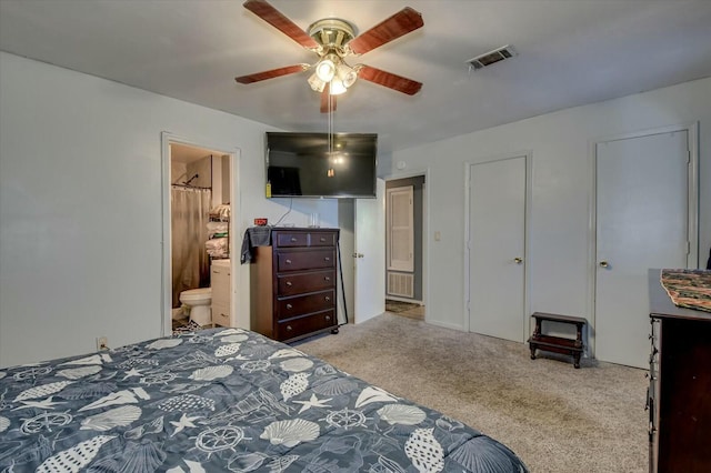 carpeted bedroom with ensuite bath and ceiling fan