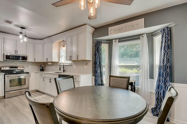 kitchen featuring sink, hanging light fixtures, plenty of natural light, stainless steel appliances, and white cabinets