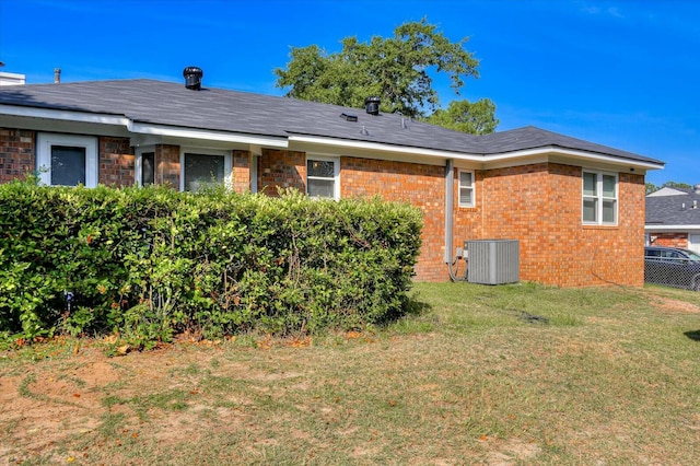 rear view of property featuring a yard and central AC unit