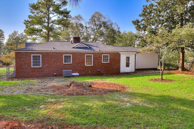 rear view of house featuring central AC and a lawn