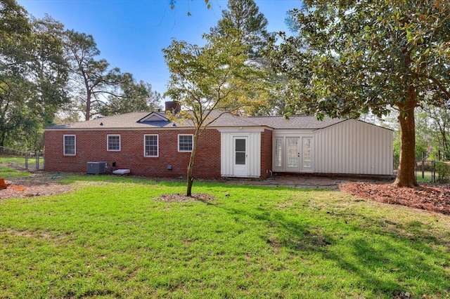 rear view of house with french doors, a yard, and central AC