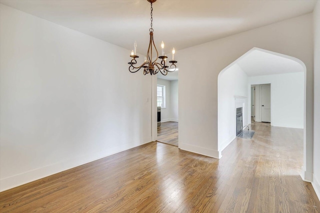 unfurnished room featuring wood-type flooring and an inviting chandelier