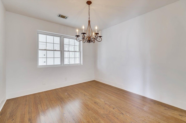 unfurnished room with wood-type flooring and a notable chandelier