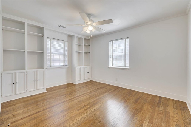 empty room with built in features, plenty of natural light, and ornamental molding