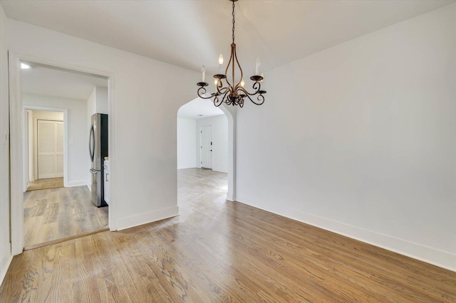 spare room with a chandelier and hardwood / wood-style floors