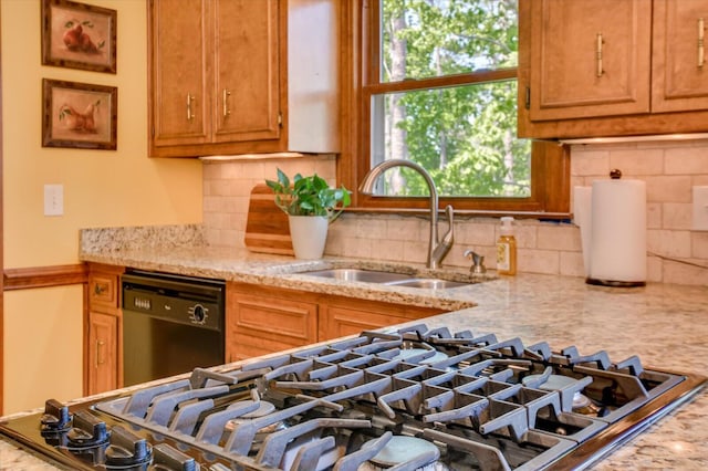 kitchen featuring black dishwasher, light stone countertops, brown cabinets, and a sink