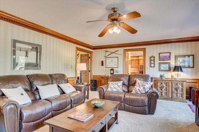 living room with carpet floors, crown molding, ceiling fan, and a wainscoted wall