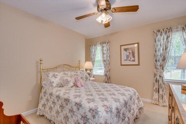 bedroom featuring light carpet, a ceiling fan, and baseboards