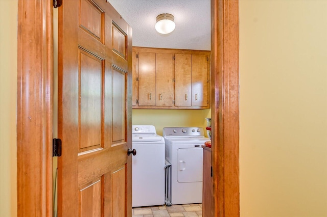 laundry room featuring cabinet space, washer and clothes dryer, and a textured ceiling