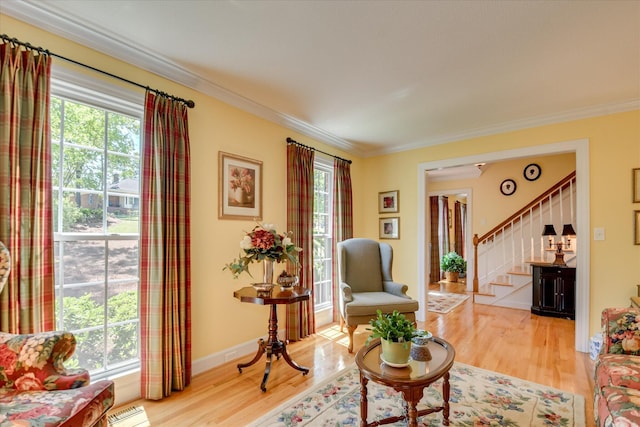living area with stairway, baseboards, crown molding, and wood finished floors
