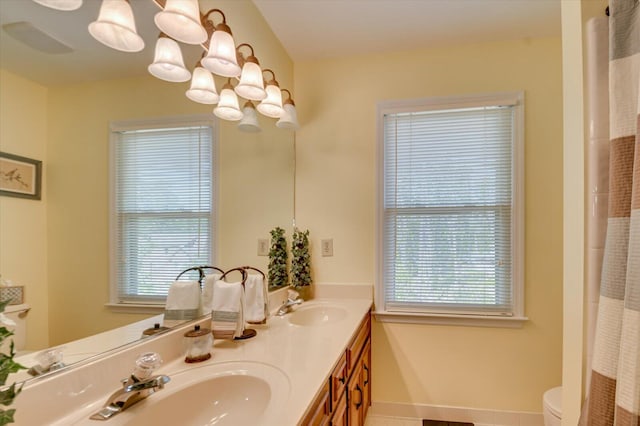full bath with plenty of natural light, a notable chandelier, and a sink