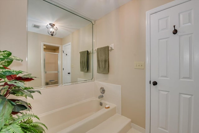 bathroom with a bath, a shower stall, baseboards, and visible vents