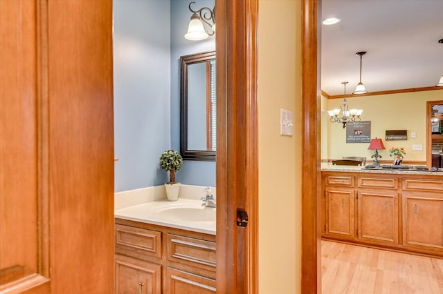 bathroom featuring a notable chandelier, wood finished floors, vanity, and ornamental molding