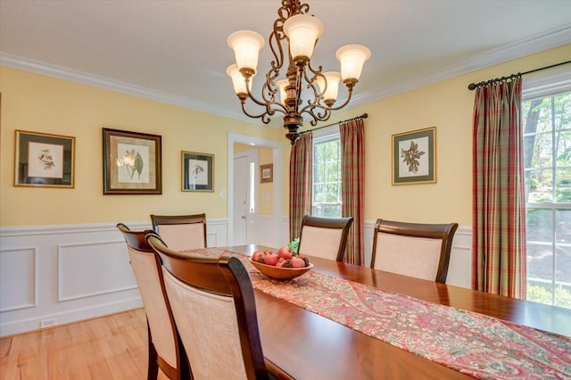 dining area featuring an inviting chandelier, a wainscoted wall, light wood-style floors, and a wealth of natural light