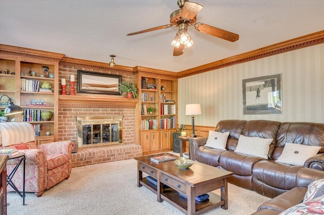 living room featuring wallpapered walls, carpet floors, crown molding, a fireplace, and ceiling fan
