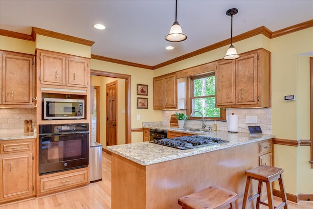 kitchen featuring a sink, gas cooktop, a breakfast bar area, stainless steel microwave, and black oven