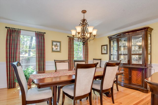 dining area with an inviting chandelier, ornamental molding, and light wood-type flooring