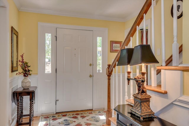 foyer entrance featuring stairway, crown molding, and wood finished floors