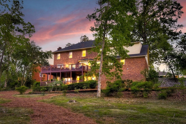 rear view of house with a wooden deck, a chimney, and brick siding