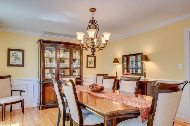 dining space with light wood finished floors, a wainscoted wall, and crown molding